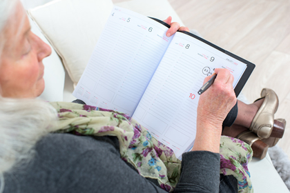 Women writing her schedule down in calendar book.