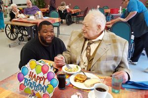 Visitor eats breakfast with Brevillier Village resident.